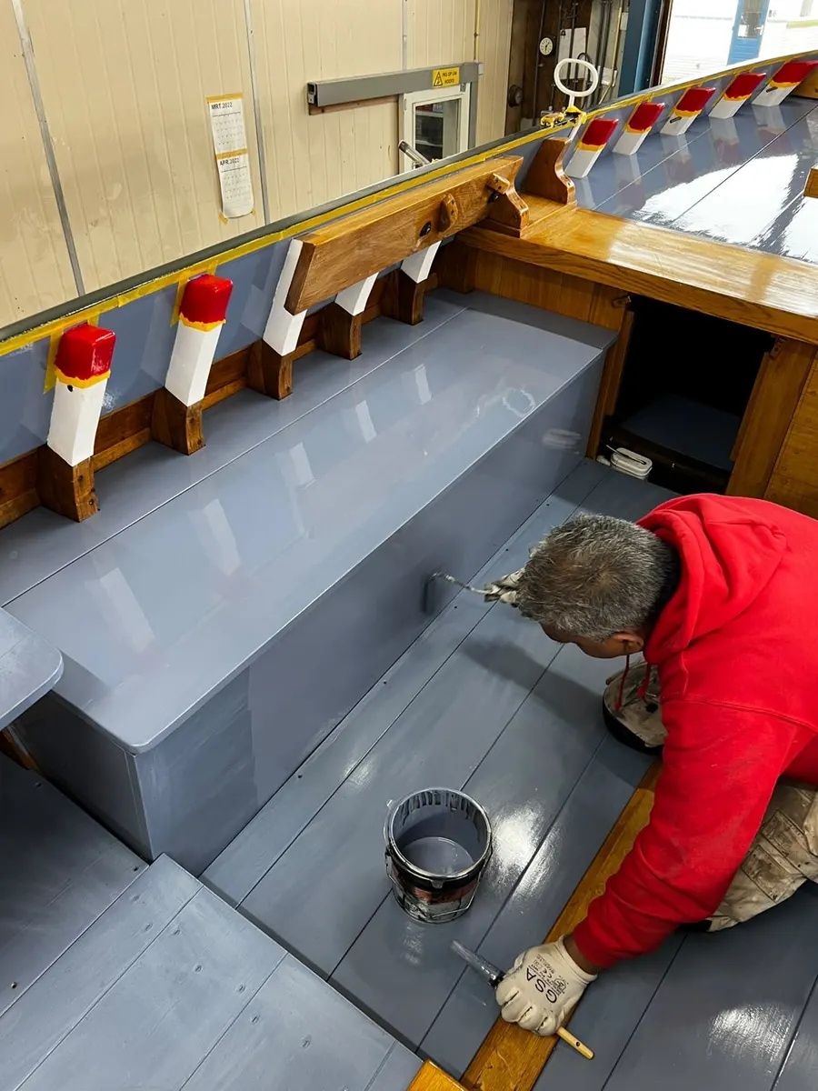 Schilder zet de kuip van een houten boot in de lak