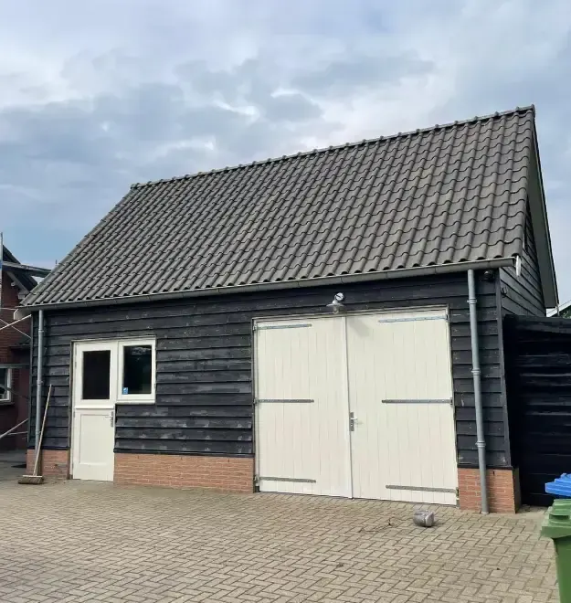 Schuur met zwart houtwerk en witte deuren